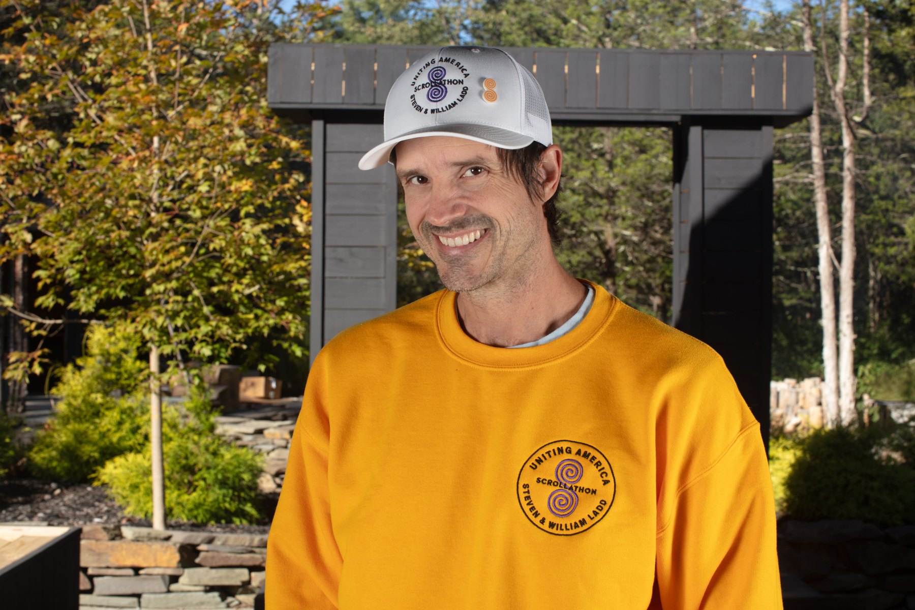 A smiling participant wearing the Scrollathon lapel pin on a white cap