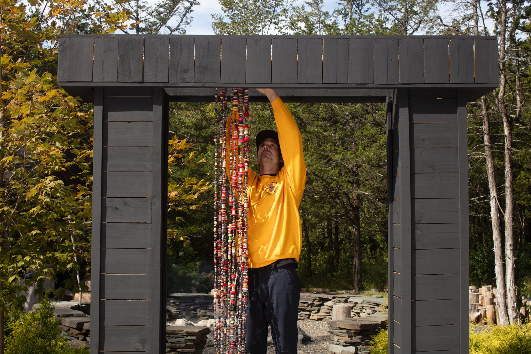 William installing colorful button hangs in the New York pillar