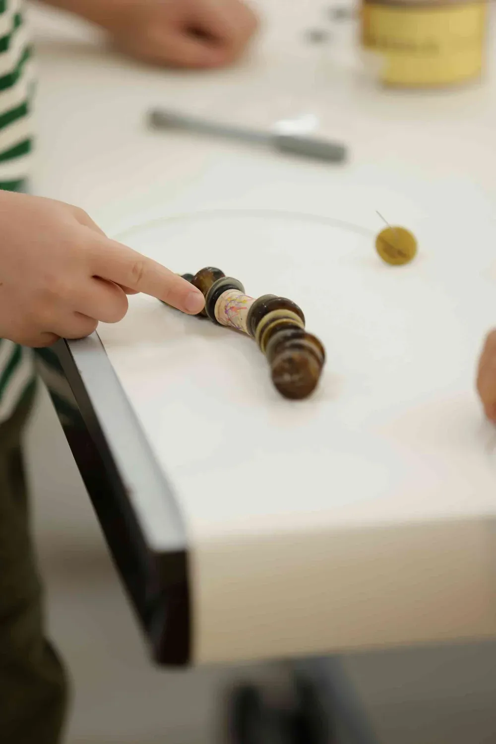 A participant working on a button hang beside a gold tin